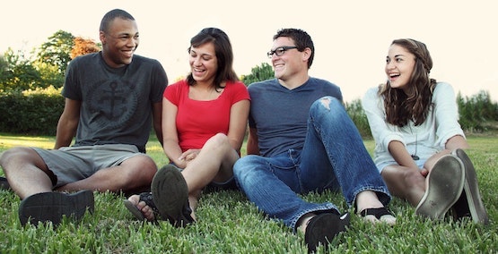 smiling-women-and-men-sitting-on-green-grass-1231230.jpg